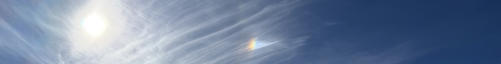Sun and a small rainbow in wispy clouds